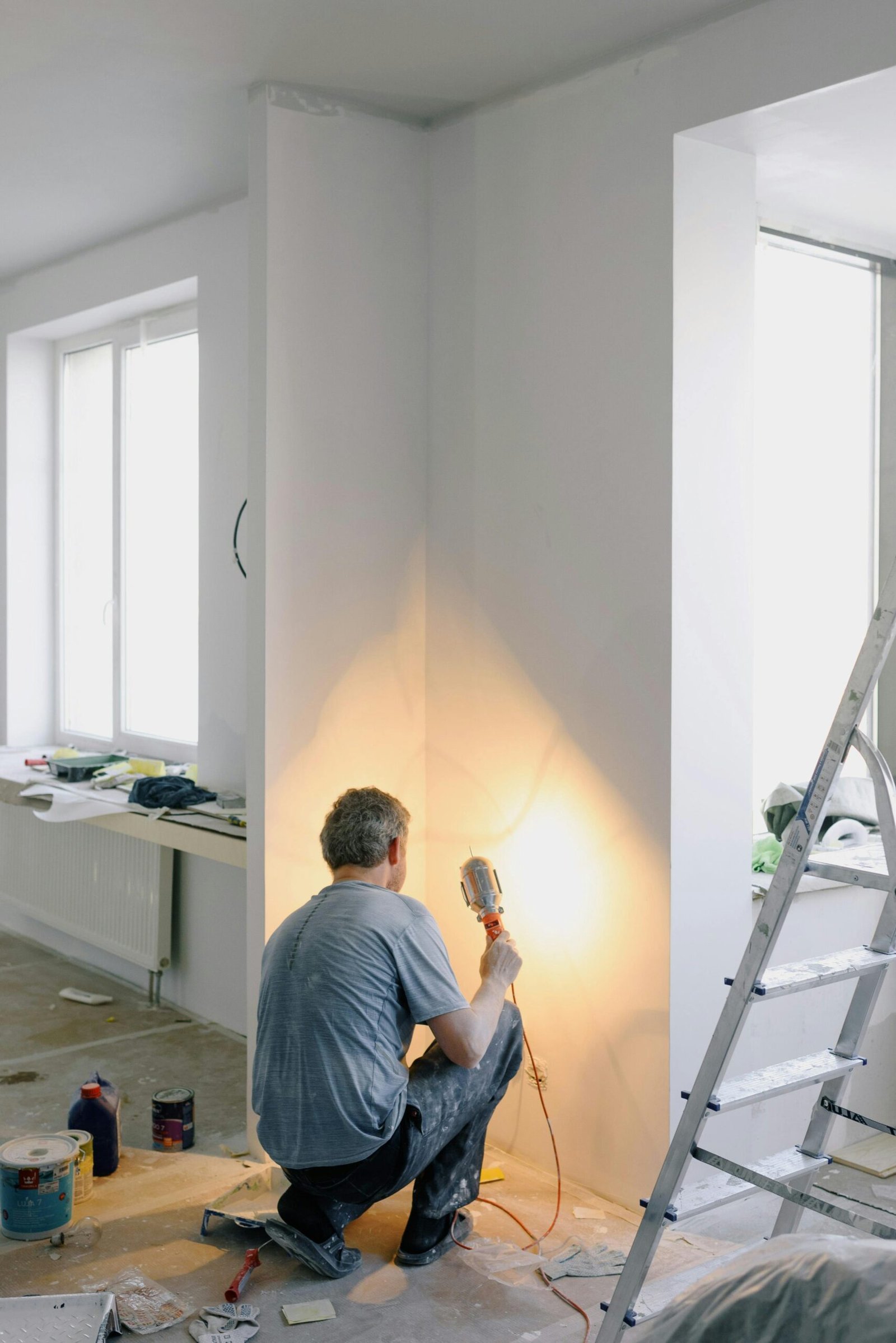 About Back view of anonymous male in dirty clothes renovating walls in home while holding lamp